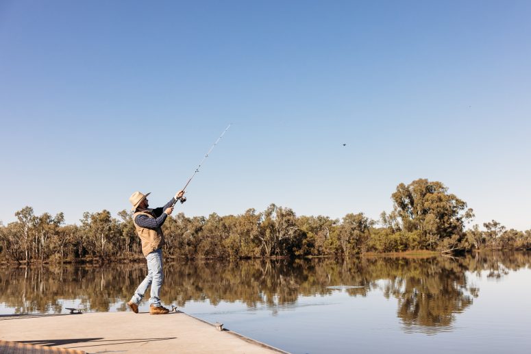 A fisherman is casting a lure from the jetty at Chinchilla Weir.
